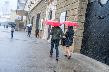 Naklejka premium person walking in the rain city of salzburg festival hall