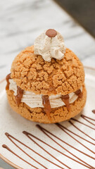 Paris Brest, a classic French dessert consist of large baked ring of choux pastry, filled with soft hazelnut cream topped with roasted hazelnut. Selective focus.