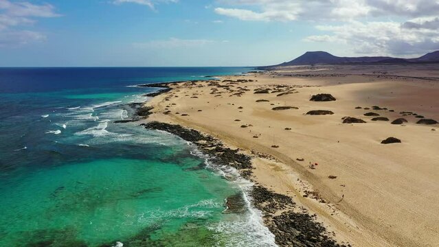 Beach with turquoise water on Fuerteventura island, Spain, Canary islands. Aerial view of sand beach, ocean texture background looping, top down view of sea waves by drone. Fuerteventura, Spain.