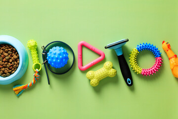 Row of pet toys, accessories, bowl of dry feed on green background. Flat lay, top view.