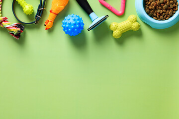 Frame border of pet accessories, toys, dry feed bowl on green table. Flat lay, top view, copy space. Pet shop banner design.