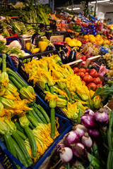 Yellow zucchini flowers and other fresh vegetables for sale on farmers market in Florence, Tuscany, Italy