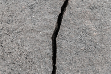 Large crack after earthquake on the soil surface of the earth damaged ground background climate...