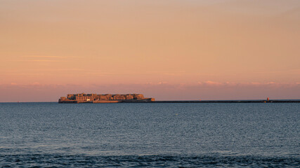 Old fortification under a sunset in the sea off Cherbourg