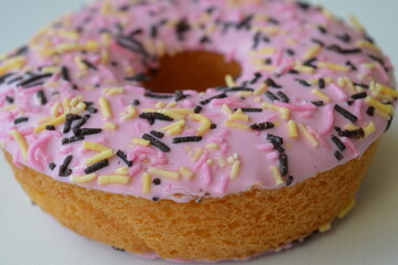 Delicious donut topped with pink sugar topping on a white background