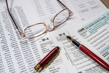 us tax form 1040 w4 w9 with pen on desk