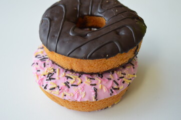 Colorful donuts with sprinkles, topped with chocolate and pink sugar topping on a white background