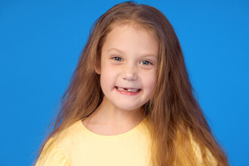 Toothless child. Cute little girl smiles broadly on a blue background. The first milk tooth fell out. The concept of pediatric dentistry and dental hygiene