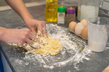  woman is fighting in the kitchen breaking eggs into flour and kneading dough into dumplings.
