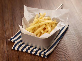 Crispy french fries in a dish isolated on napkin dark wooden table side view singapore food