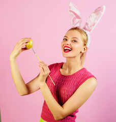 Easter girl in bunny ears painting eggs. Rabbit woman with colored egg and paint brush.