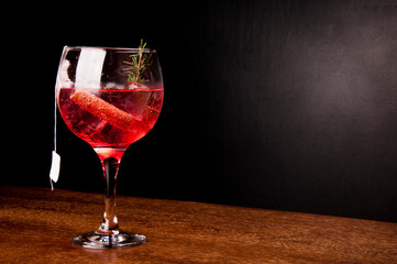 cocktail tea gin ice cinnamon and alecrin angle top view on wooden table, dark leather bench