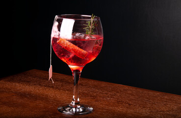 cocktail tea gin ice cinnamon and rosemary front view on corner wooden table