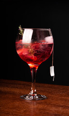 cocktail tea gin ice cinnamon and rosemary front view on wooden table