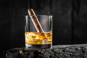 Cigar in a glass of whisky with ice.