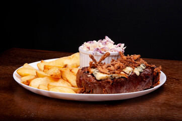 food plate with juicy beef steak with blue cheese crispy onion coleslaw salad and rustic potatoes on wooden table.