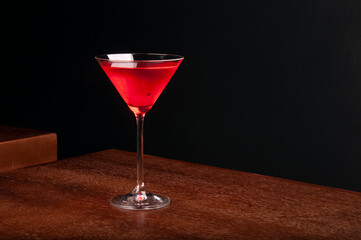 martini cocktail glass with cherry on wooden table with dark background front view corner