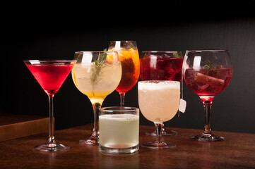 mixology assorted and colorful cocktails collection on wooden table and dark leather bench