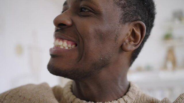Portrait of a happy african man showing the keys to a new apartment or house, filming himself on camera and rejoices in the purchase