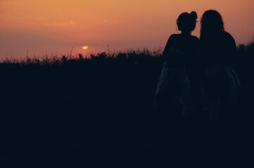 Silhouette of a two attractive young woman posing on the beach during sunset