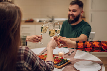 Friends sitting at a kitchen table and toasting during a dinner part