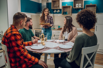 Group of friends enjoying dinner while sitting at the kitchen table together