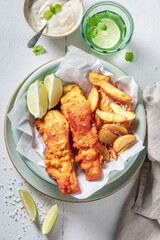 Grilled fish and chips with sauces and lime.