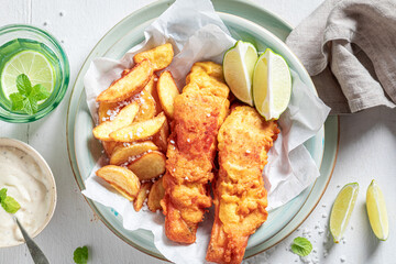 Tasty fish and chips with sauces and lime.
