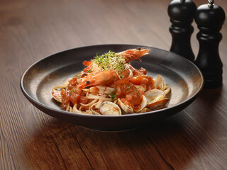 Seafood Marinara Pasta in a dish isolated on dark wooden table side view singapore food