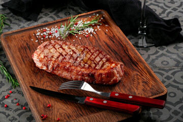 Grilled New york or striploin beef steak served with seasonings, herbs and a glass of wine on a...