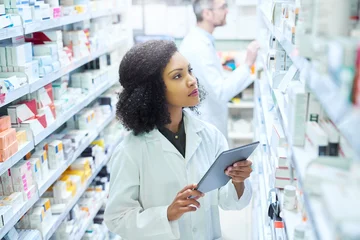 Foto auf Acrylglas Apotheke Mobile apps that have pharmacy management covered. Shot of a young woman using a digital tablet to do inventory in a pharmacy.