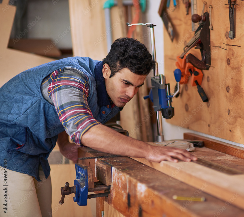 Poster details make the difference. shot of a focused handyman measuring a piece of wood while working in h
