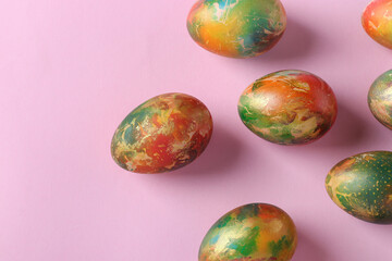 Marble eggs painted with food colors for Easter on a pink background. Top view. Close up