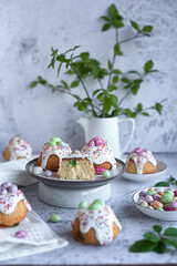 Easter cakes for children: candied fruit muffins covered with icing sugar and decorated with candy on a light concrete background
