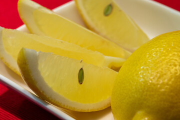 Slices of juicy lemon on a white plate. Lemon on a red background.