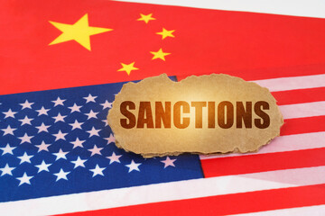 On the flags of the USA and China lies a cardboard sign with the inscription - Sanctions