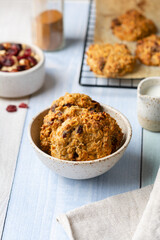Healthy oatmeal-nut cookies with flakes, dried fruits, raisins, cranberries, cinnamon in a ceramic bowl on a colored wooden background. Sugar-free baking concept