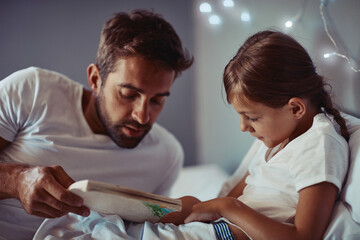 Its the calmest and quiet part of the day. Cropped shot of a father reading a bedtime story to his...