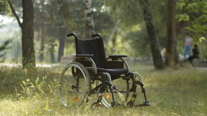 A wheelchair for disabled people is standing in a public park, close-up