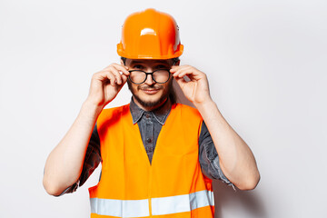 Portrait of young construction worker in orange equipment, on white background.