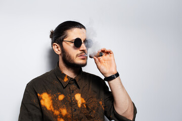 Side portrait of young man with a cigar wearing sunglasses on white background.