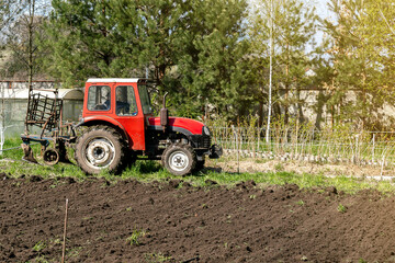 Modern red tractor machinery plowing agricultural field meadow at farm at spring autumn. Farmer cultivating and make soil tillage before seeding plants and crops, nature countryside rural scene