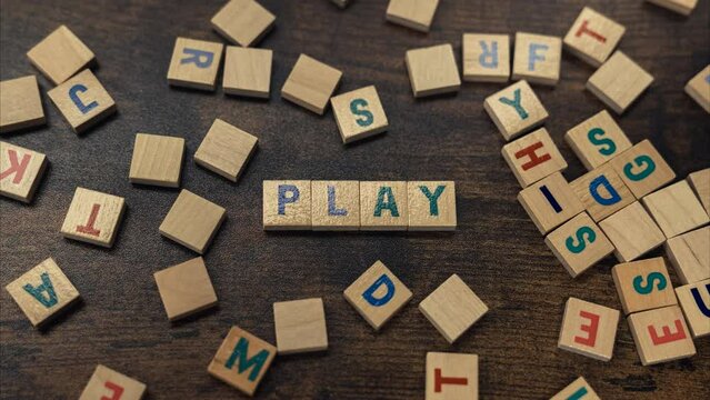 Zoom in the word PLAY made of aligned wooden blocks with alphabet letters on the brown wooden table . High quality 4k footage