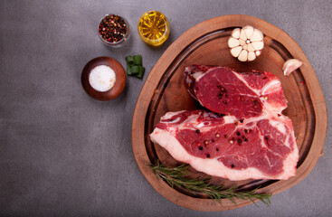 cut of raw meat with fat t-bone steak in the butcher's shop on wooden board with seasonings garlic olive oil