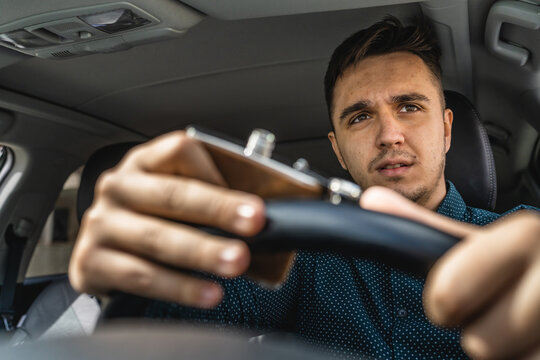 One man caucasian male drinking alcohol from flask while drive a car drunk close up on drink alcoholism and alcohol abuse concept intoxicated dangerous nervous driver hands on the steering wheel
