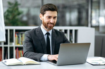 Handsome caucasian man, manager, lawyer, economist, sits at his desk in front of a laptop, in a...