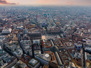 Fototapeta premium Aerial view of Piazza Duomo in front of the gothic cathedral in the center. Drone view of the gallery and rooftops during the day. Milan. Italy,