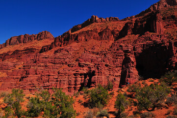 Hiking below the deep red sandstone cliffs around the trailhead to the Fisher Towers, Moab, Utah, Southwest USA