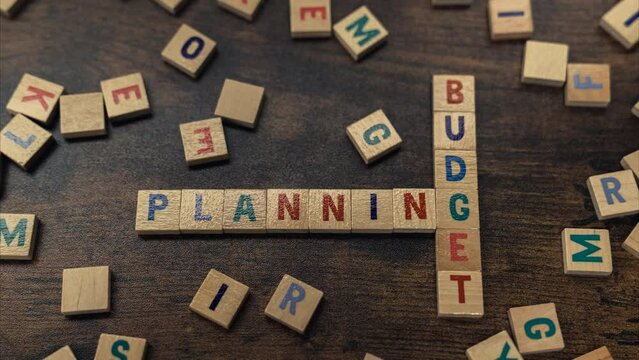 A phrase PLANNING BUDGET made of wooden blocks with letters put together perpendicularly . High quality 4k footage