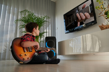 Independent student connected to learn to play electric guitar at home. Kid guitarist concept